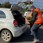 Man carrying foodbank box putting on the car