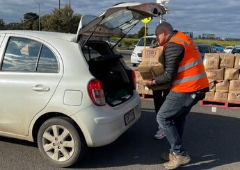 Man carrying foodbank box putting on the car