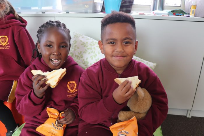 School Breakfast Club Children recipient smiling while holding their sandwiches 