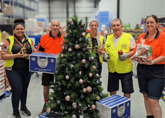 five people smiling while holding food donations