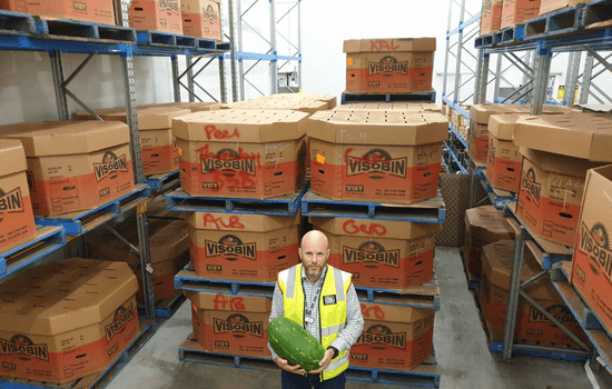 behind mike are boxes of watermelons he donated